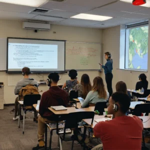 A photo of a group of people in a classroom. They (1)